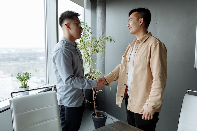 two people shaking hands in a gray office